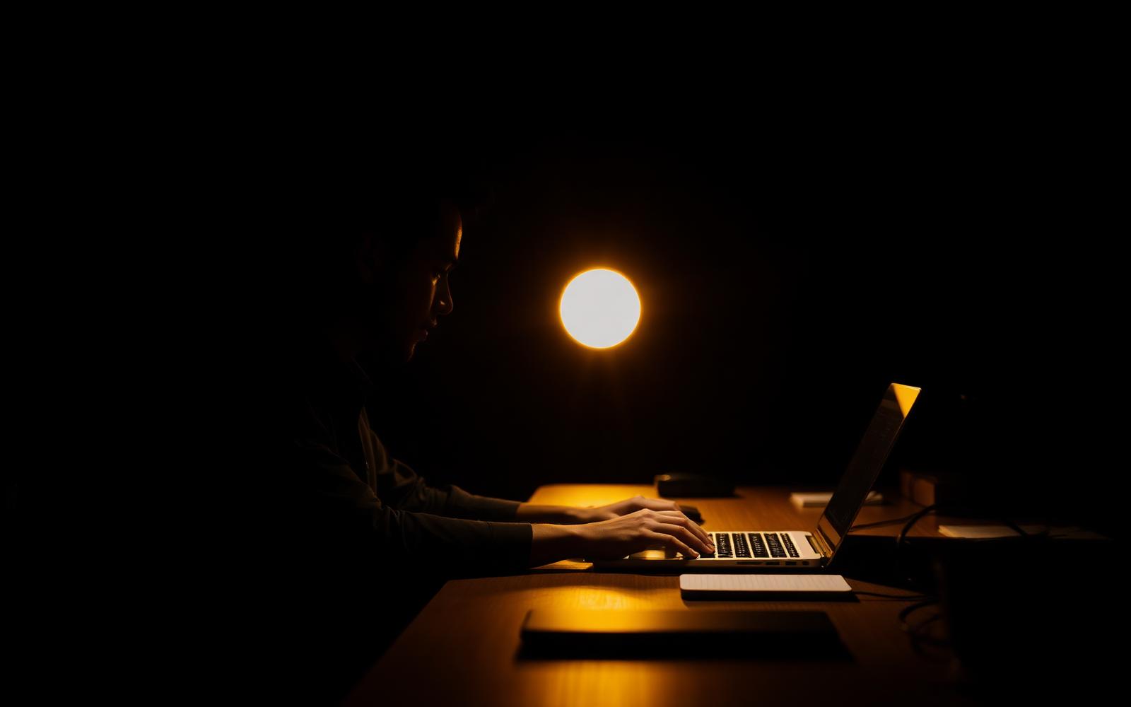 Personne travaillant sur un ordinateur portable dans un bureau à l'ambiance chaleureuse